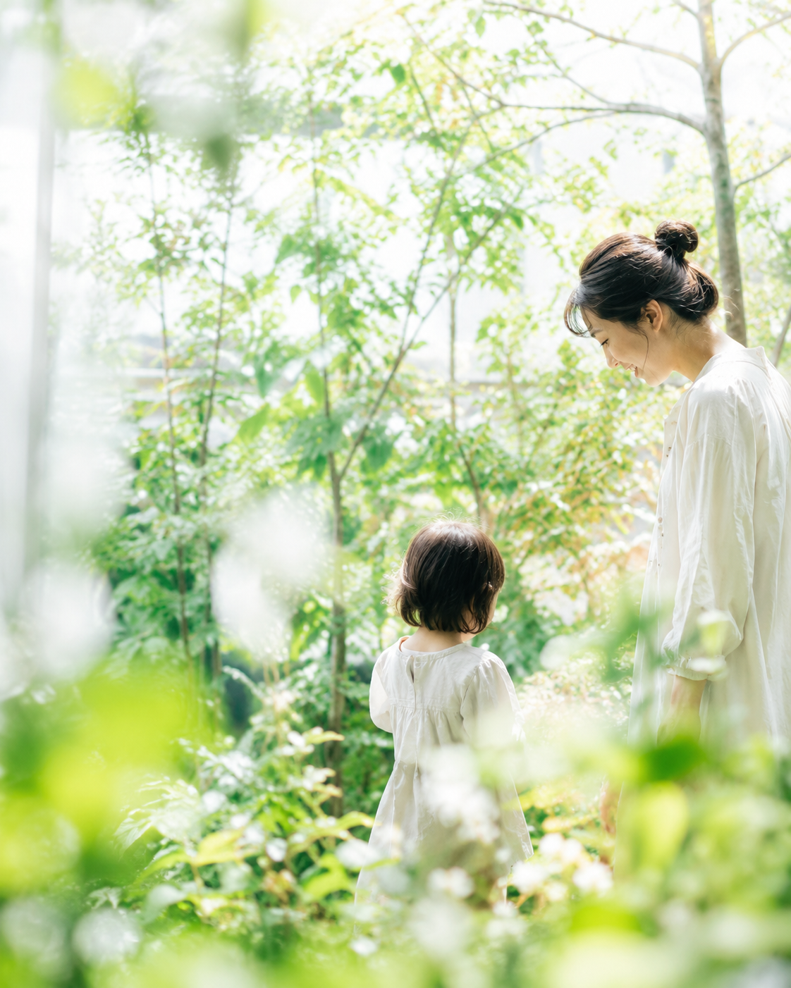緑に囲まれた庭で母と子が静かに過ごす写真