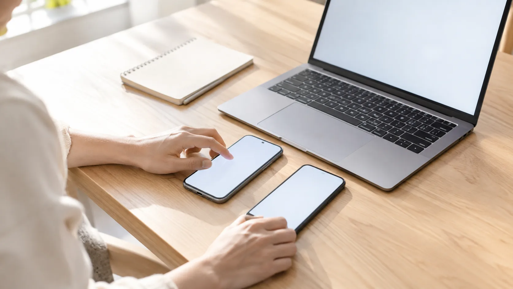 ノートパソコンとスマートフォンを並べて見比べている手元